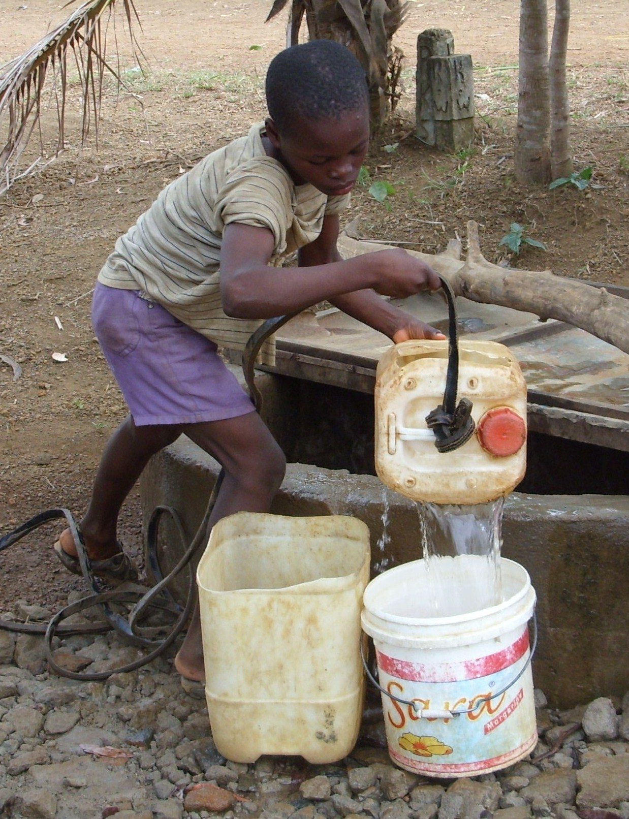 A child drawing water from an exposed well in Liberia