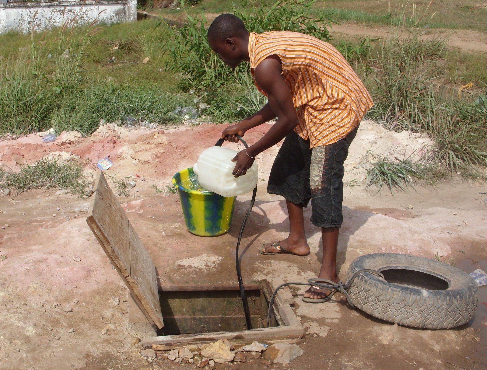 Man fetching water from unsafe well in Liberia